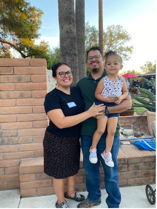 A Mexican American family posting for a picture. The mom and daughter have medium light skin and the dad has medium skin.