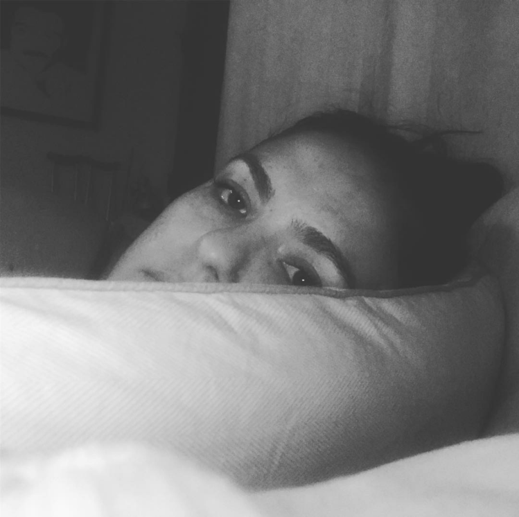 A black and white photo of a pregnant Alisha, her eyebrowns looking amazing while she exhaustedly rests on a pillow